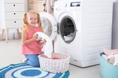 Photo of Adorable little girl doing laundry at home