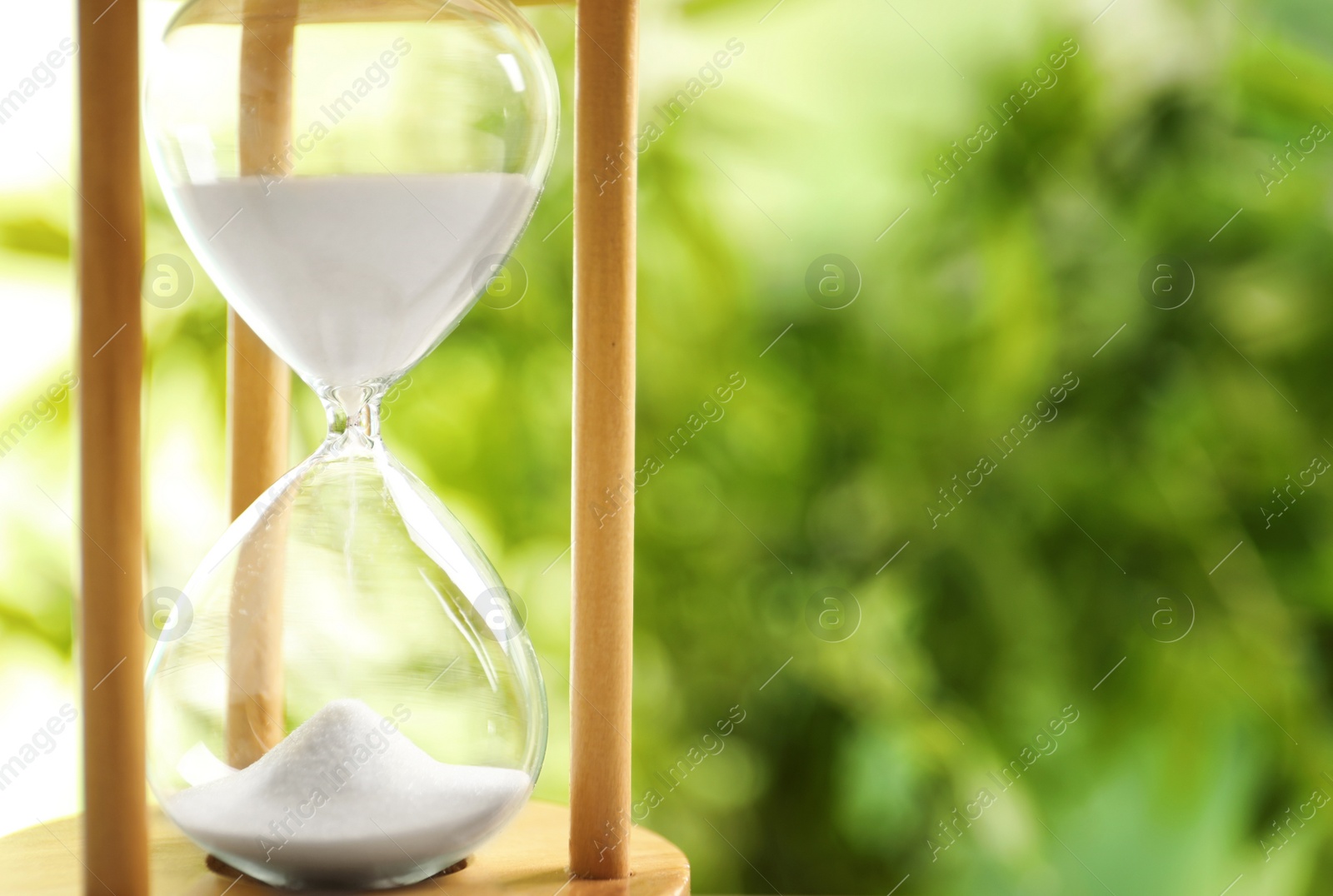 Photo of Hourglass with flowing sand on blurred background. Time management