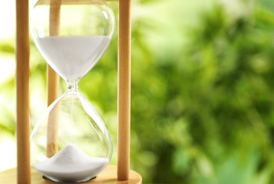 Hourglass with flowing sand on blurred background. Time management