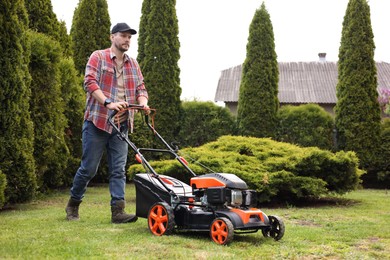 Photo of Man cutting green grass with lawn mower in garden