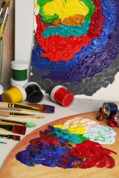 Abstract colorful painting and different artist's tools on textured table