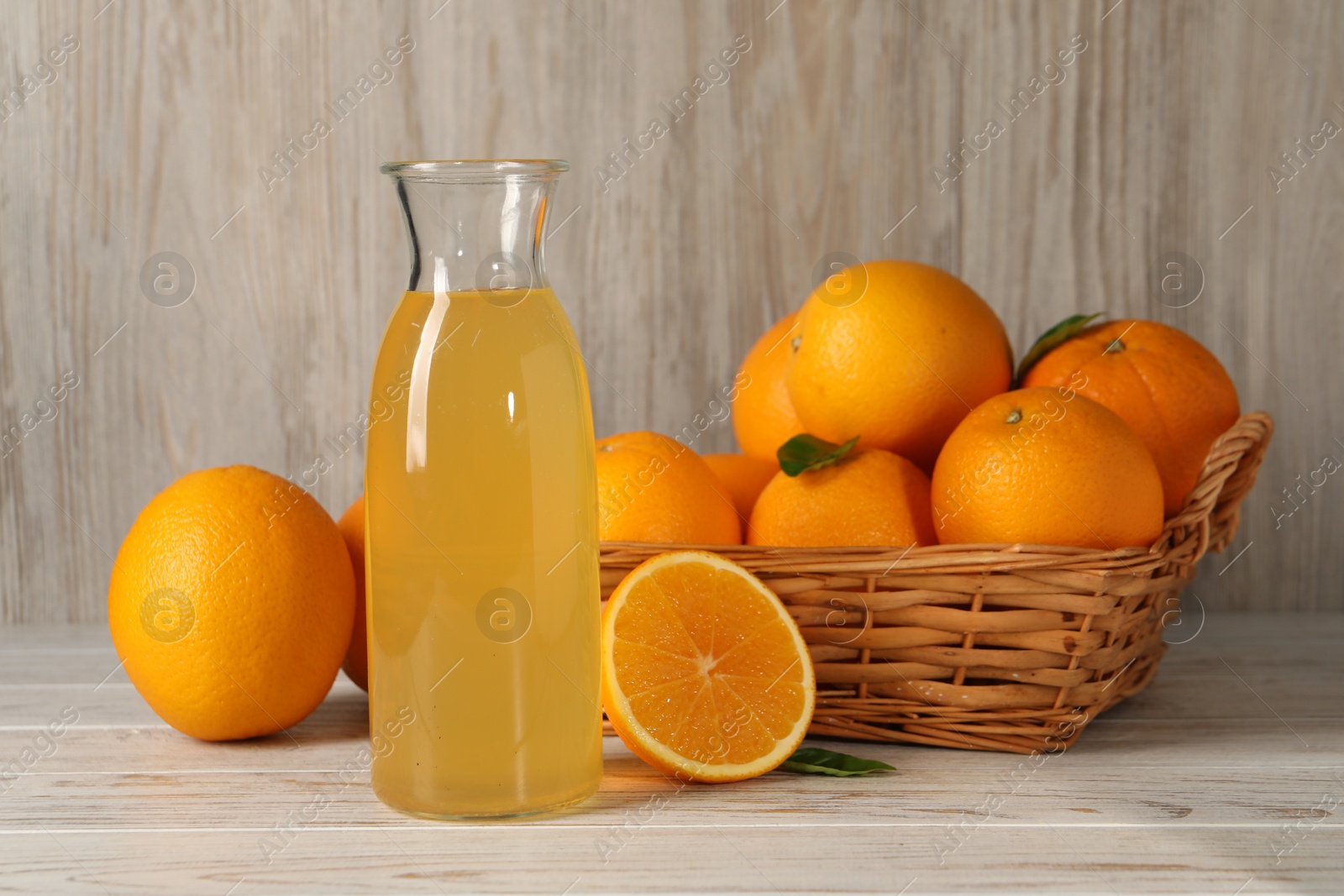 Photo of Many ripe oranges and fresh juice on light wooden table