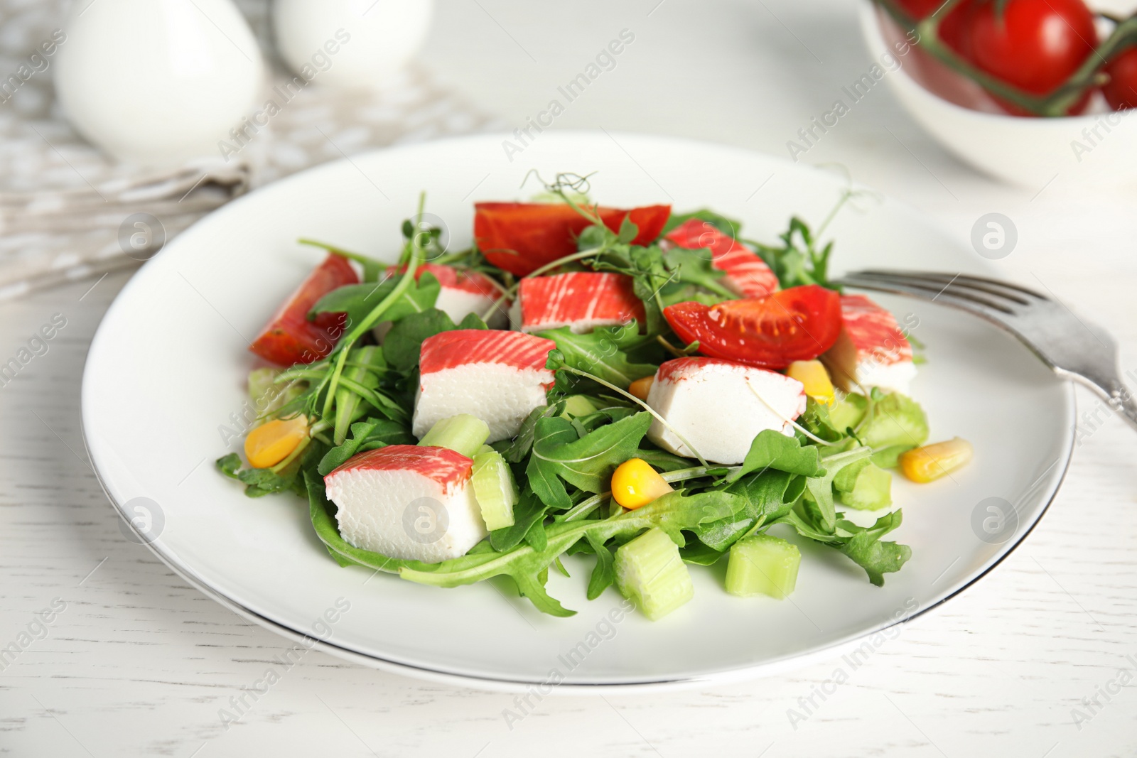 Photo of Tasty crab stick salad served on white table, closeup
