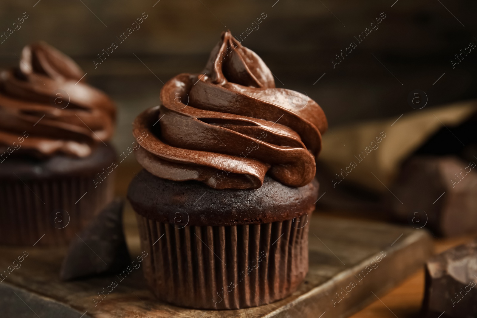 Photo of Delicious chocolate cupcakes with cream on wooden board, closeup