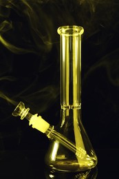 Photo of Glass bong and smoke on black background, toned in yellow. Smoking device