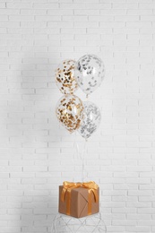 Photo of Bright balloons and gift near brick wall. Party time