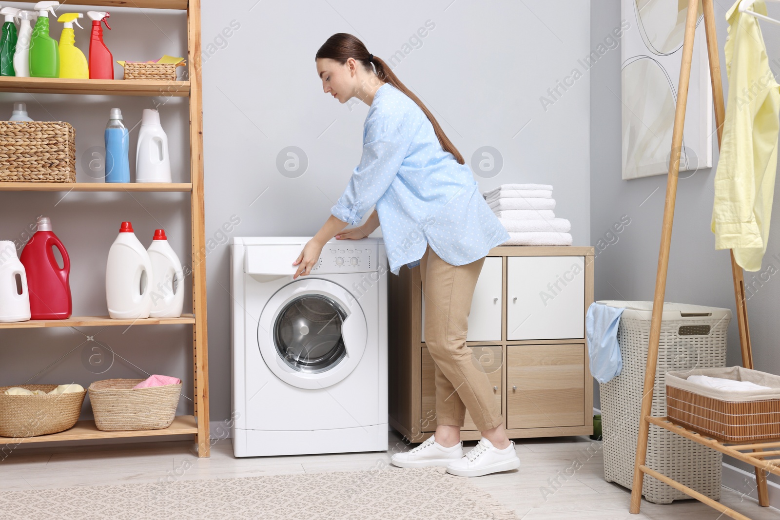 Photo of Beautiful woman near washing machine in laundry room