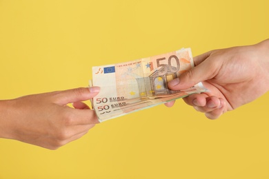 People with Euro banknotes on yellow background, closeup