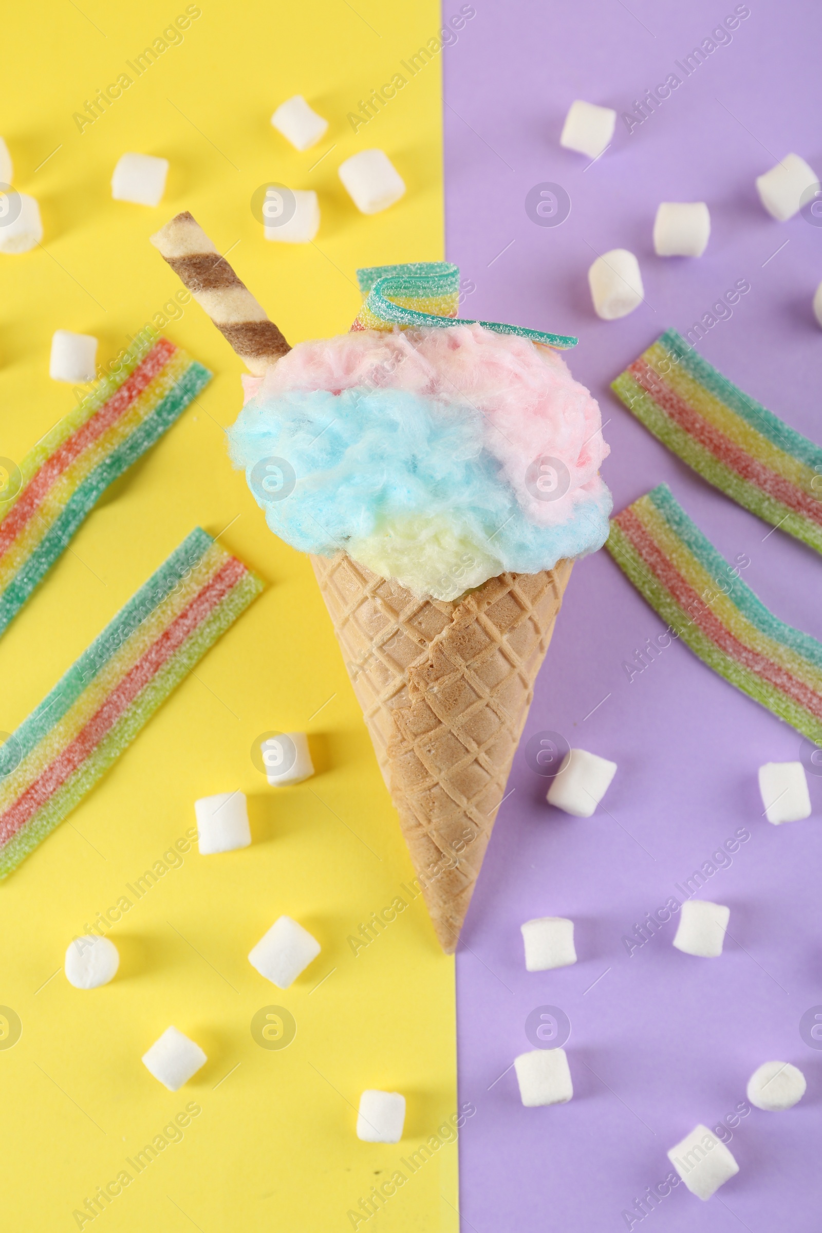 Photo of Sweet cotton candy in waffle cone and marshmallows on color background, flat lay