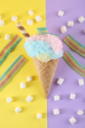 Photo of Sweet cotton candy in waffle cone and marshmallows on color background, flat lay