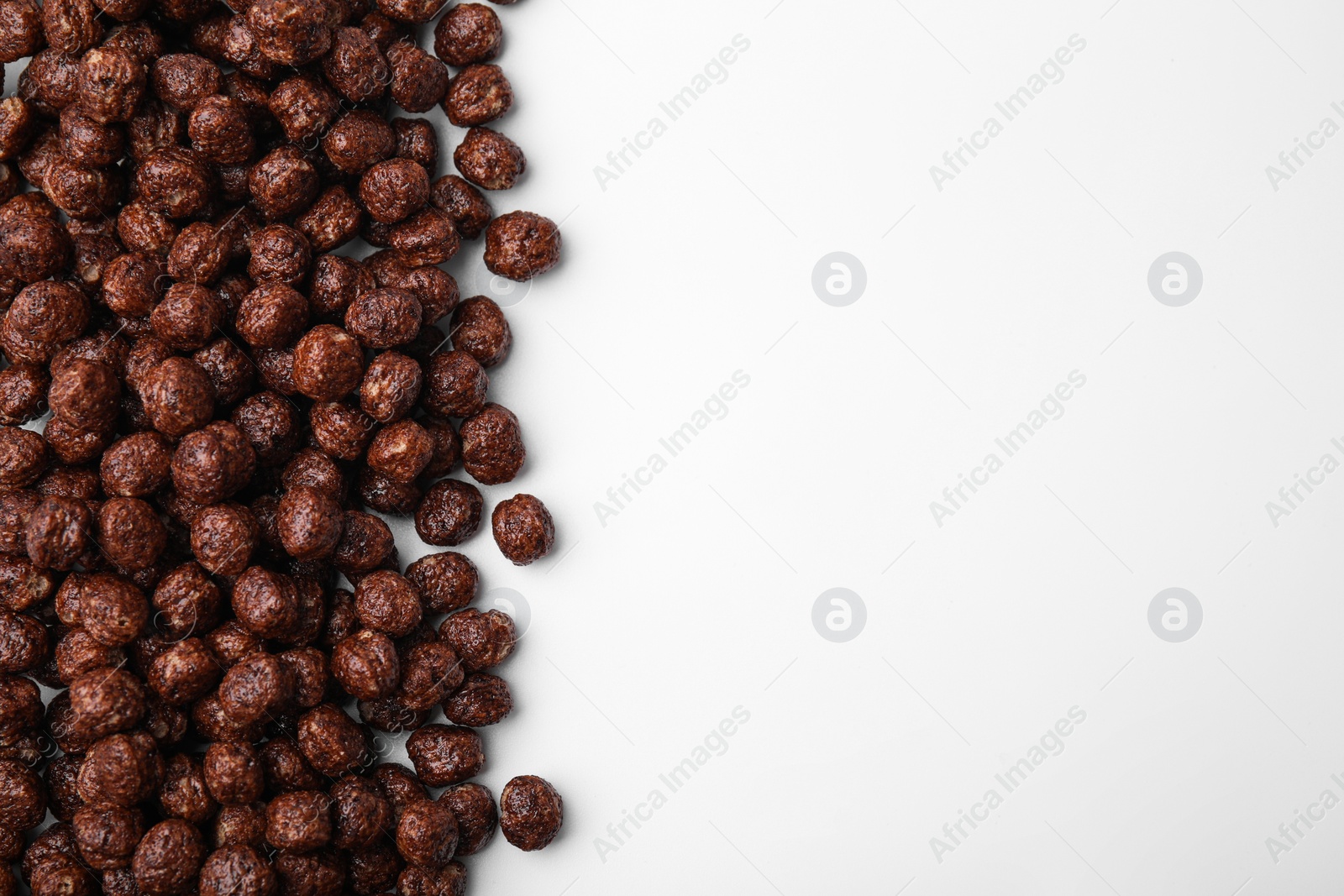 Photo of Tasty chocolate cereal balls on white background, flat lay. Space for text