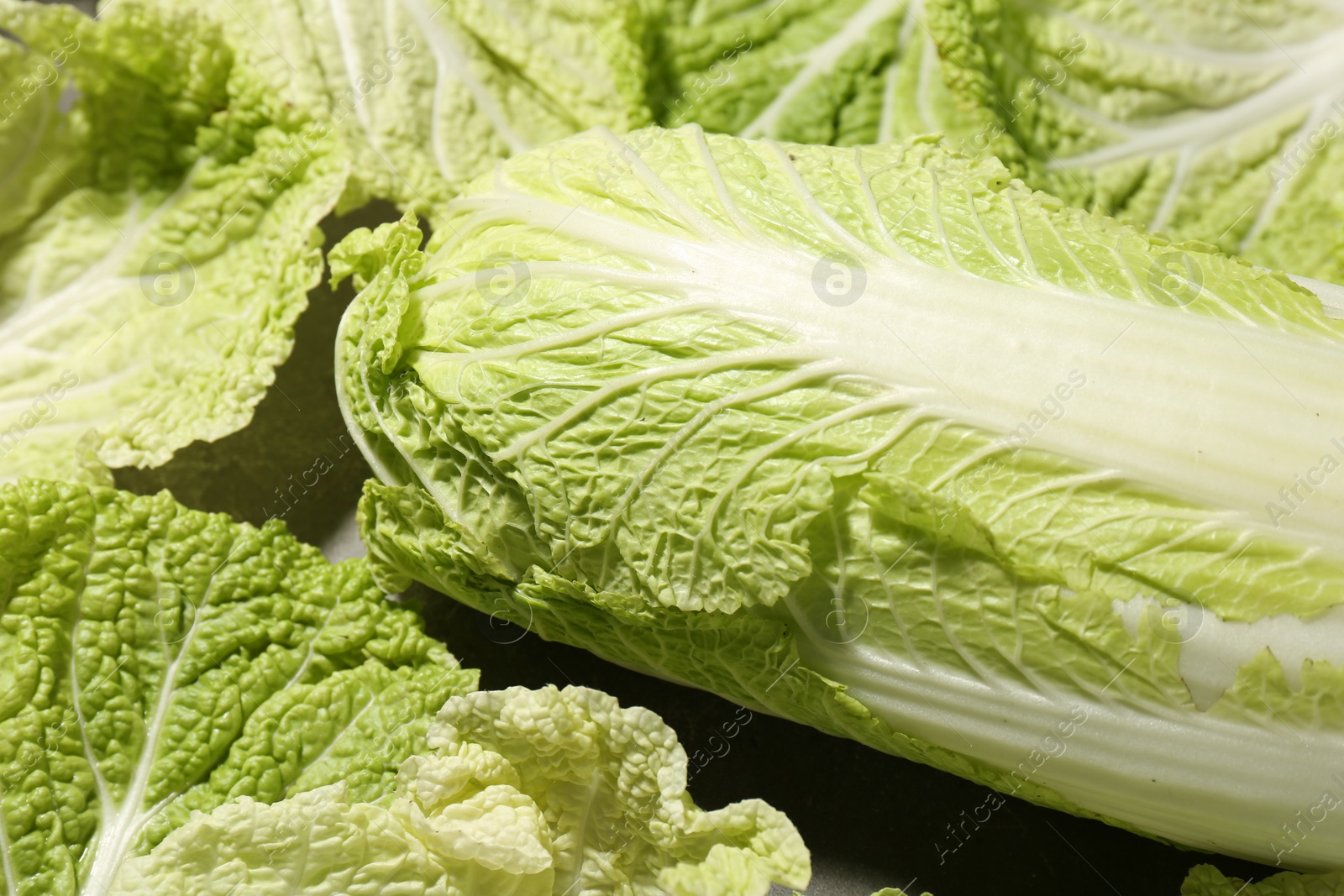 Photo of Fresh ripe Chinese cabbage and green leaves on table, closeup