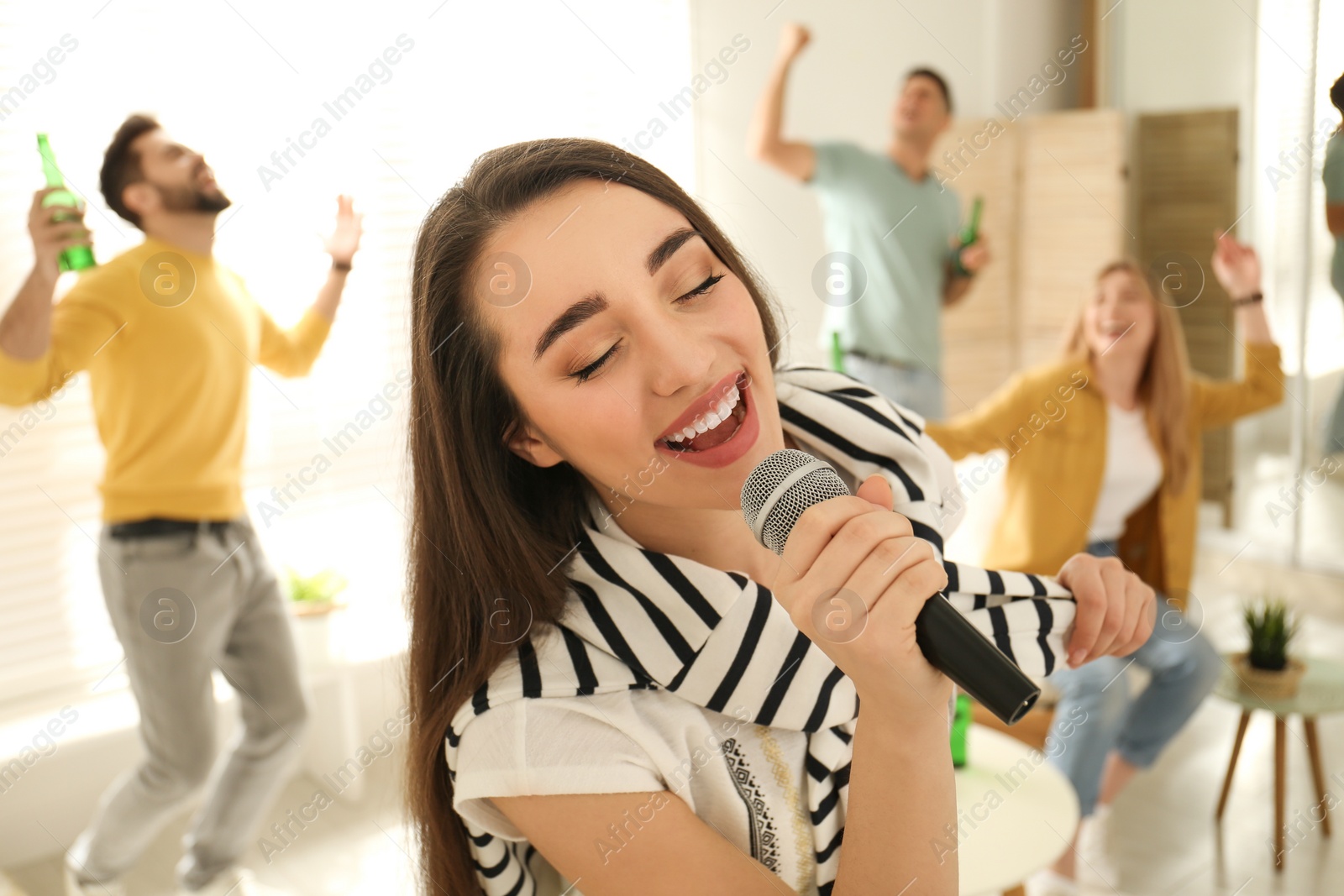 Photo of Young woman singing karaoke with friends at home