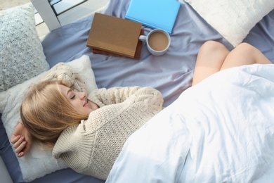 Photo of Beautiful young woman sleeping at home, top view. Winter atmosphere