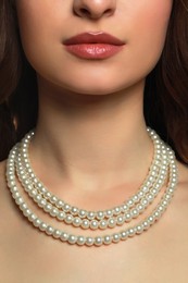 Photo of Young woman wearing elegant pearl necklace, closeup