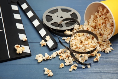 Composition with popcorn, film reel and clapperboard on wooden background