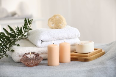 Spa composition. Burning candles, soap, towels and loofah on soft grey surface