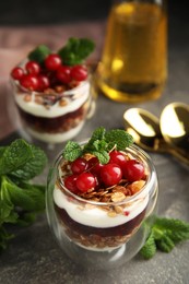 Photo of Delicious yogurt parfait with fresh red currants and mint on grey table, closeup