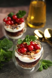 Delicious yogurt parfait with fresh red currants and mint on grey table, closeup