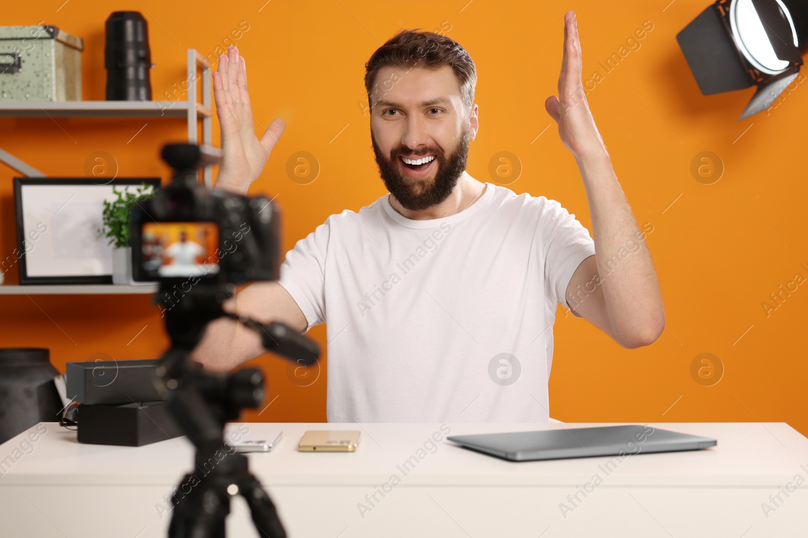 Photo of Smiling technology blogger explaining something while recording video at home