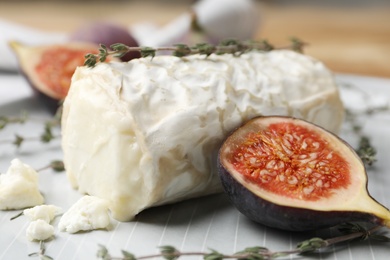 Delicious goat cheese with figs and thyme on plate, closeup