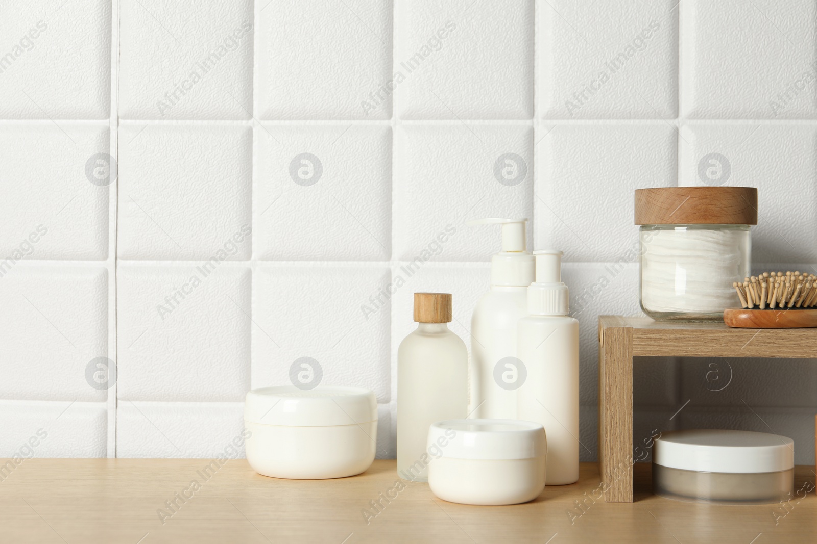 Photo of Different bath accessories and personal care products on wooden table near white tiled wall, space for text