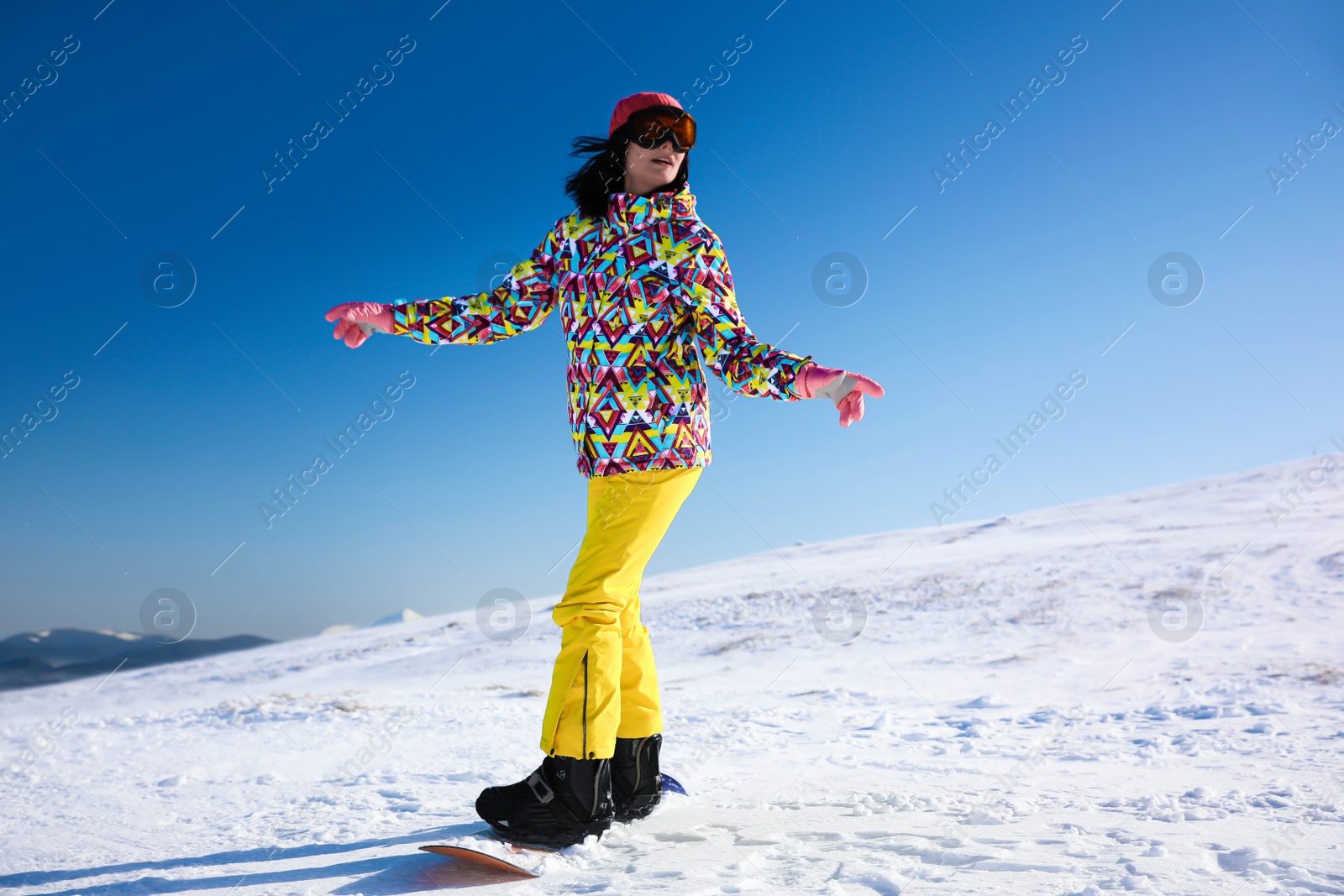 Photo of Young woman snowboarding on hill. Winter vacation