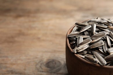 Raw sunflower seeds on wooden table, closeup. Space for text