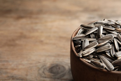 Photo of Raw sunflower seeds on wooden table, closeup. Space for text