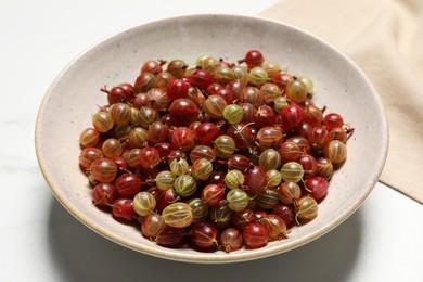 Photo of Plate of fresh ripe gooseberries on white table, closeup
