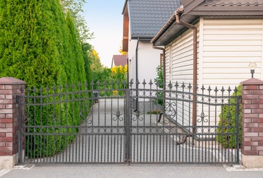 Photo of House and gates of beautiful fence with iron railing outdoors