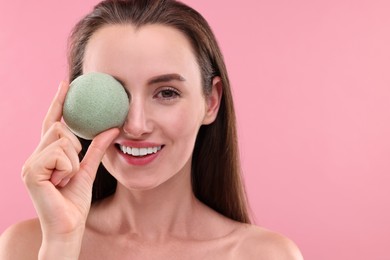 Happy young woman holding face sponge on pink background. Space for text