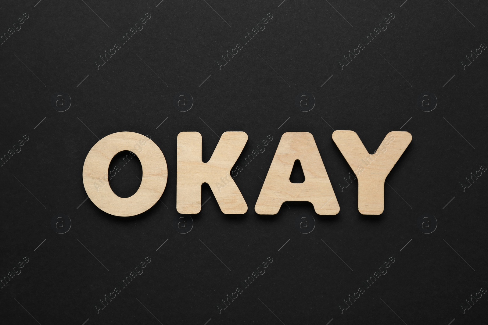 Photo of Word Okay made of wooden letters on black background, top view