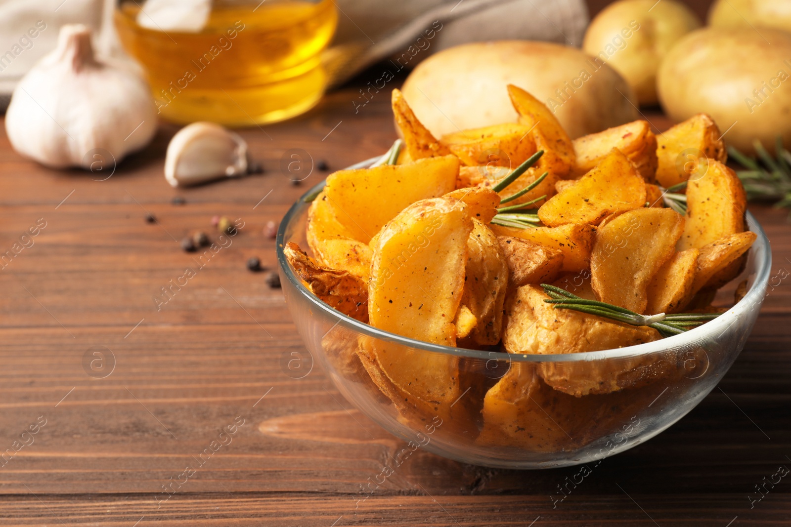 Photo of Glass bowl of delicious oven baked potatoes on table, closeup. Space for text