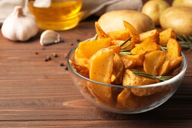 Photo of Glass bowl of delicious oven baked potatoes on table, closeup. Space for text