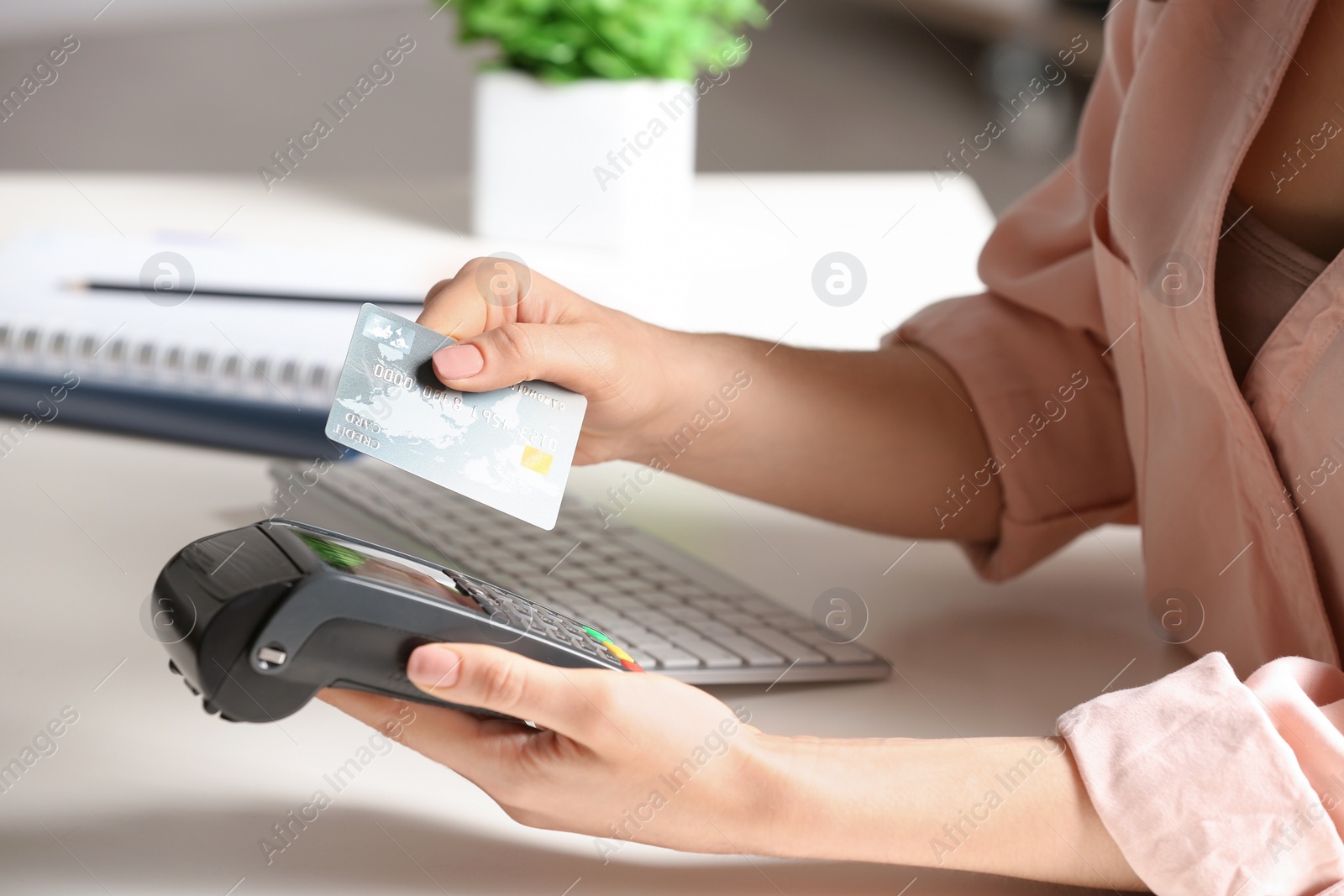 Photo of Woman using modern payment terminal at table indoors, closeup