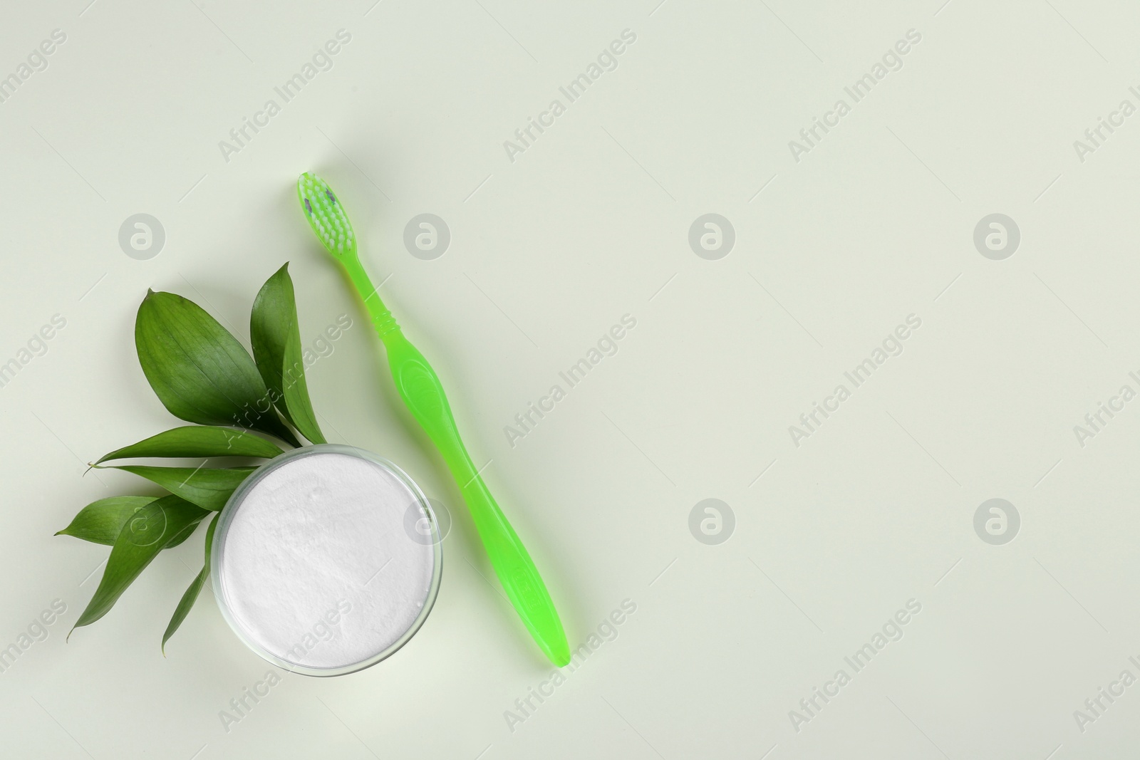 Photo of Toothbrush and bowl of baking soda on beige background, flat lay. Space for text