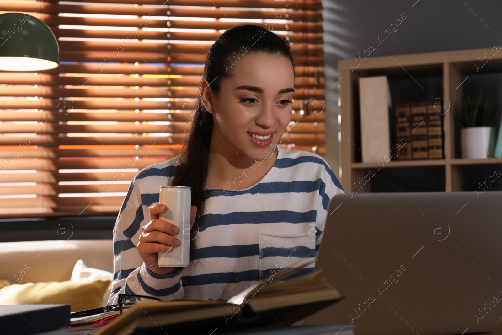 Photo of Young woman with energy drink studying at home