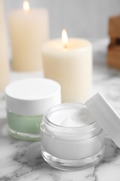 Jars of facial cream on white marble table