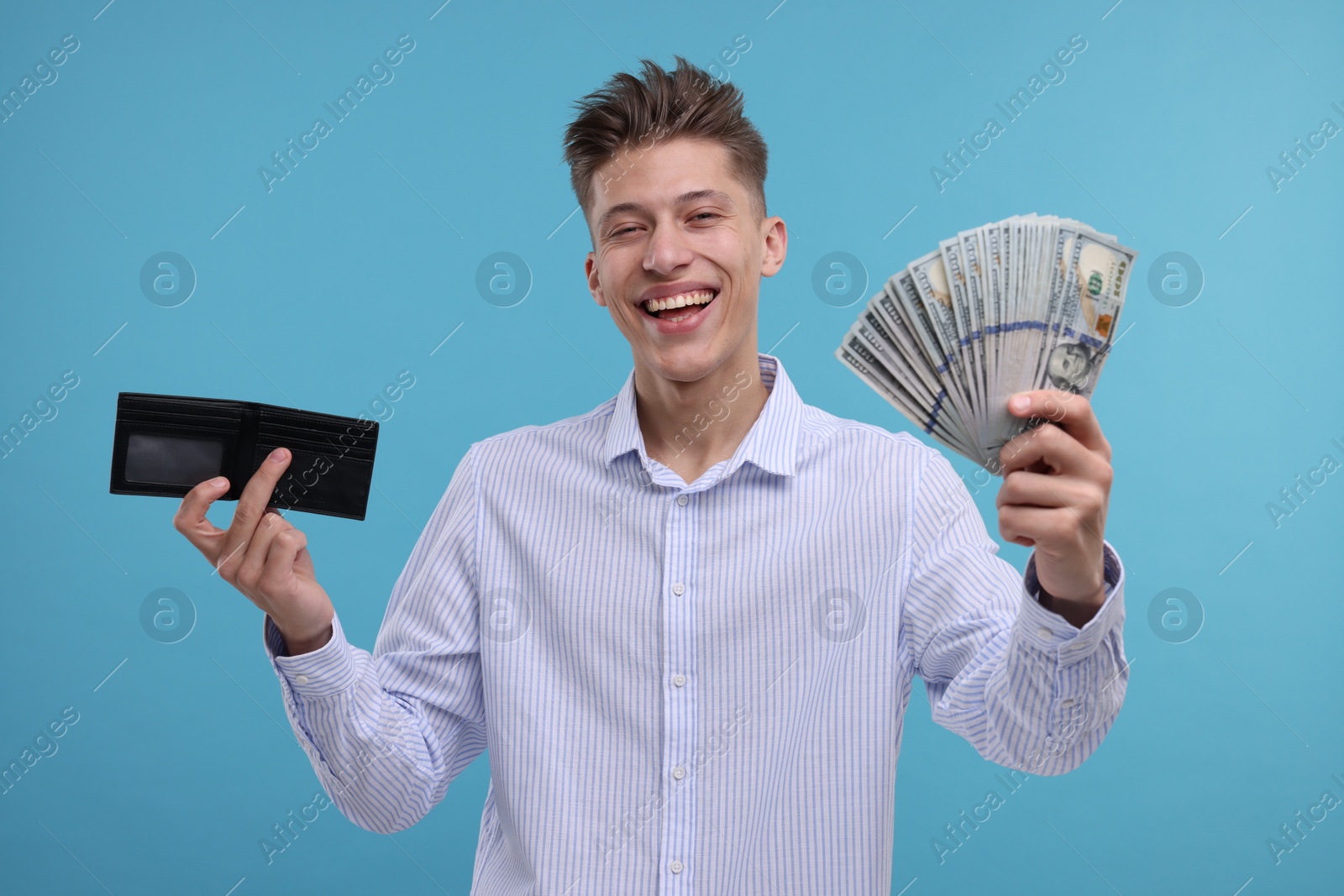 Photo of Happy man with wallet and dollar banknotes on light blue background