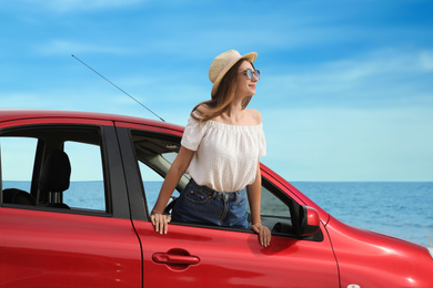 Photo of Happy woman leaning out of car window on beach. Summer vacation trip