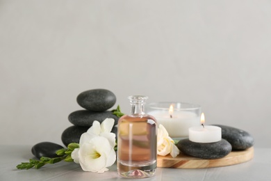 Photo of Beautiful composition with essential oil, spa stones and candles on table