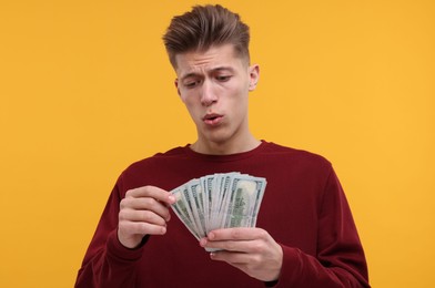 Photo of Handsome man with dollar banknotes on yellow background