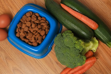 Photo of Dry pet food and products on wooden background, flat lay