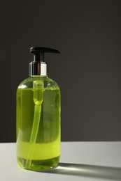 Photo of Bottle of liquid soap on grey table. Space for text