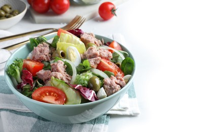 Photo of Bowl of delicious salad with canned tuna and vegetables on white table, space for text