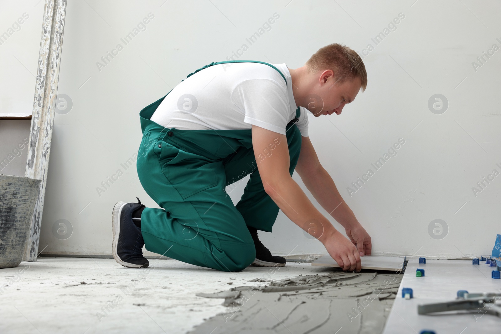 Photo of Worker installing ceramic tile on floor near wall