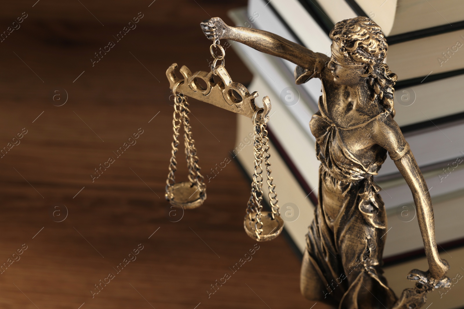 Photo of Symbol of fair treatment under law. Figure of Lady Justice and books on wooden table, closeup with space for text