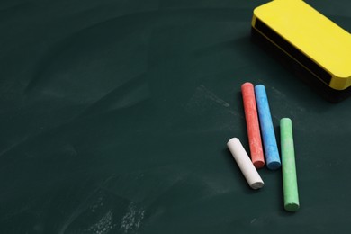 Photo of Colorful chalks and duster on green board, space for text