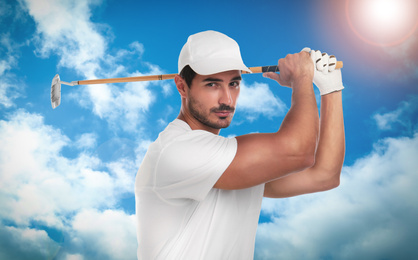 Young man playing golf against blue sky